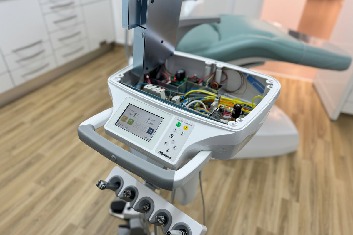 Dental delivery unit with open cover showing internal components on a wooden floor.